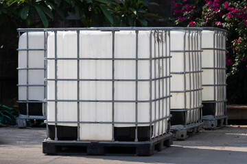 white ibc containers on black plastic pallet on concrete floor.