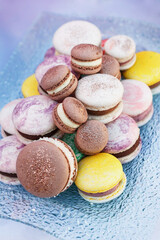 Soft focus of macaroni cakes of different colors on a glass plate close-up. Birthday dessert. Sweets for the candy bar. Festive sweets. Party treat. Holiday pastries. French confectionery.
