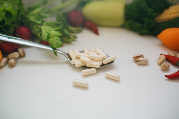 Fototapeta na wymiar capsules of probiotics and vitamin D3 on the surface of spoon near fresh vegetables and nuts