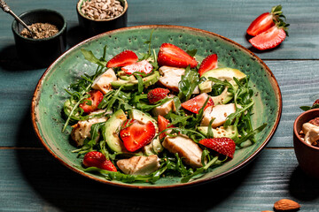 Fresh strawberry salad with arugula, chicken, avocado and strawberries. Plate with a keto diet food. Top view