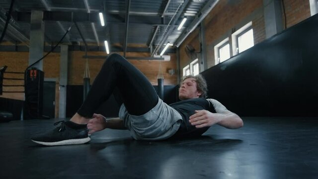 Active kickboxer working on abc at gym. Sportsman doing crunches in sport club