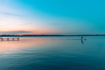 Naklejka na ściany i meble stand up paddling on the lake at sunset 