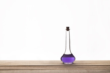 Vintage glass perfume bottle on the wooden table. Purple liquid. Copy space.