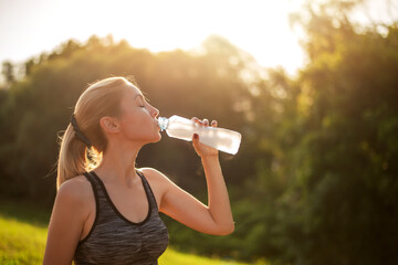 Young woman drinking water from plastic bottles
