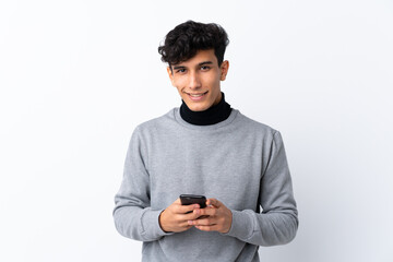Young Argentinian man over isolated white background sending a message with the mobile