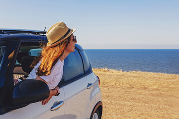 A young woman in a hat looking out of window of a car