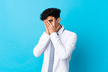 Young Argentinian businessman over isolated blue background covering eyes and looking through fingers