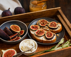 Toasted whole wheat bread with figs, cream cheese, honey, walnuts served on brown wooden rustic tray. Healthy food concept. Beautiful breakfast or dessert. Selective focus with copy space.