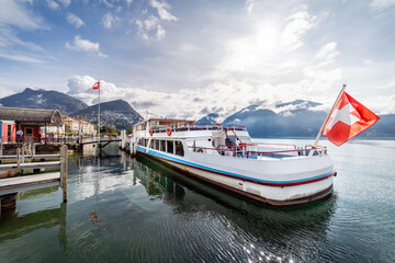 Lugano, Tessin, Schweiz. Ein Kursschiff an der Schiffsanlegestelle. Schweizer Flagge, Tourismus, Urlaub, Reisen.
