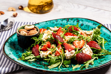 Close up salad with arugula, strawberries and cheese brie, camembert. Healthy food diet food concept. recipe background