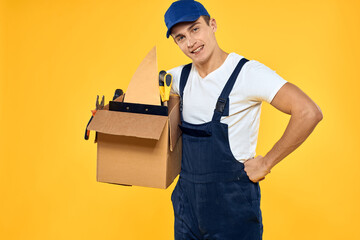 worker with box in hand tools loader yellow background