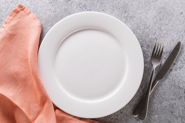 Empty ceramic plate, napkin and cutlery on the table, top view. Food background