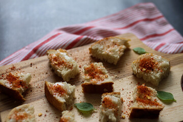 Bread slices spread with lard sprinkled with red hot ground pepper and served on the wooden cutting board. Old Traditional Serbian meal. 