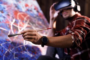 Talented male artist wearing virtual reality headset in creative modern studio. Artist works on abstract oil painting. Abstract Modern Art.