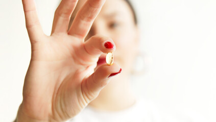 Close up of woman with pill cod liver oil Omega-3. Holding soft shell D-vitamin capsule. Diet nutrition and healthy concept. Vitamin E, A Fish Oil.