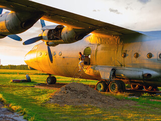 Yo ungwoman standing at plane ladder going to board, outdoors, airport. Old Soviet military airplane, sunset time. Close up of a Abandoned Historic Aircraft. Close up of propeller engine. 