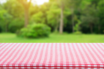 Red checkered tablecloth texture top view with abstract green bokeh from garden in morning background.For montage product display or design key visual layout and summer season.