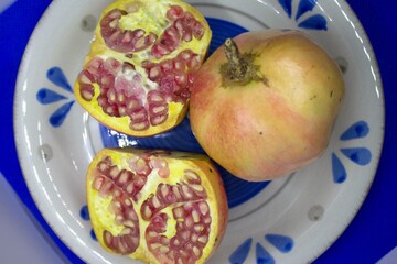 evocative close-up of whole pomegranate and cut in two parts on a blue plate