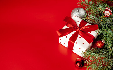 Christmas composition on a red background with a white gift box, with a red ribbon with fir...
