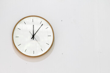 Analog clock on white wall background with copy space.