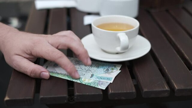 Crop man with money on terrace in cafe