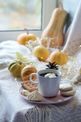 Obraz na płótnie Canvas A cup of coffee, meringues, pumpkins, leaves, a warm blanket on the windowsill, the concept of home comfort, relaxation, loneliness, Thanksgiving, autumn season