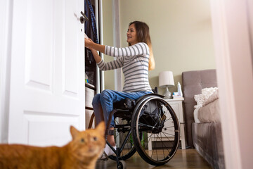 Woman in wheelchair sorts through her wardrobe
