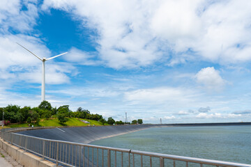 landscape of wind turbine for generate renewable electricity and the dam under blue sky