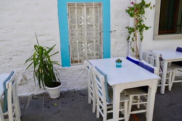 Authentic Bodrum Streets by the Sea. Blue window, white tables street traditional Turkish Bodrum cafe. Cozy outdoor cafe near beautiful Aegean Sea.