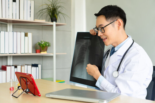 young asian doctor showing film x-ray of right foot to the patient via computer using video call conference program. telemedicine and online medicine concept