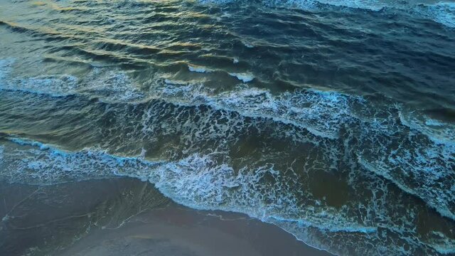 Beautiful calm aerial view of peaceful waves gently crashing on sandy beach shore