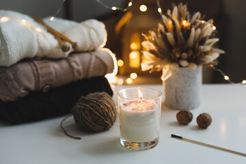 Christmas background. Candle, knitted sweater, christmas decorations and bokeh lights background. Christmas cozy mood still life