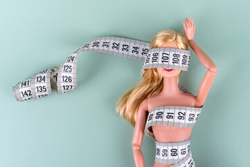 Doll wrapped in measuring tape. Tied up unrecognizable plastic doll, weight loss, fasting and...