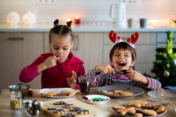 Children decorating Christmas cookies and having fun at home