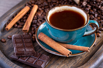 A cup of coffee, chocolate, cinnamon, coffee beans on a wooden tray. Life style.
