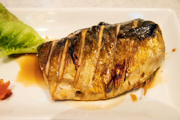 Grilled Saba fish on white plate; easy meal with healthy food.