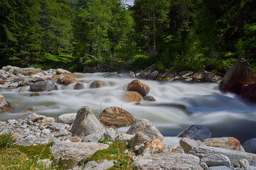 Langzeitbelichtung eines Wasserlaufs &uuml;ber Steine in den Bergen mit seidenem Wasser