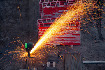 Industrial worker sawing metal with many sharp sparks
