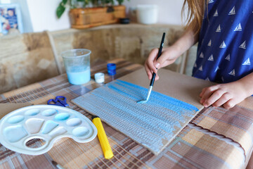 the girl draws blue gouache cardboard, makes a background, sits in the home kitchen