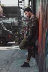 Fototapeta na wymiar Mexican young man leaning on the wall, urban portrait