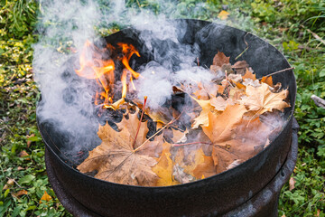 Burning in  barrel of autumn yellow maple leaves, the view from above, a lot of smoke, goodbye autumn summer, autumn mood