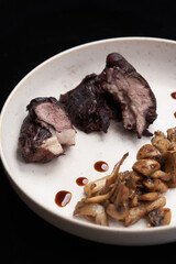 Baked lamb chops and mushrooms on a white plate.