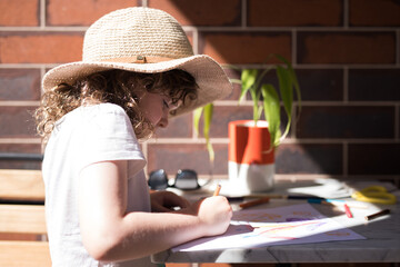 young girl child seated at her outdoor study desk at home learning school from home with colored pencils paper drawing learning in the sunshine