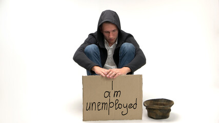 Sad unemployed man on white background. Job loss and poverty concept. Young man sits and begs for money.