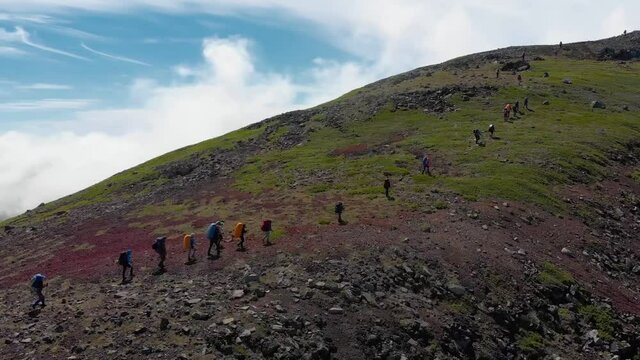 aerial view of group people hiking along trail path in sunny day. people hikers climbing mountain, team work, travelling, trekking.