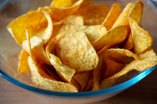 Mexican Appetizer Cornmeal Nachos With Spices In A Glass Round Plate Stand On A Brown Table Side View . Snack