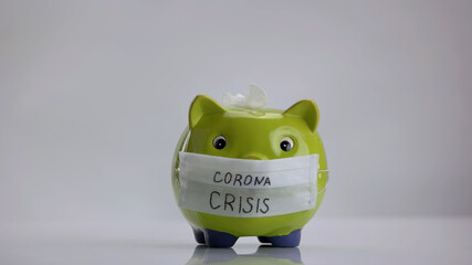 Corona crisis concept. Green piggy bank with medical mask.