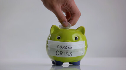 Hand puts glove into piggy bank. Donation for coronavirus pandemic.