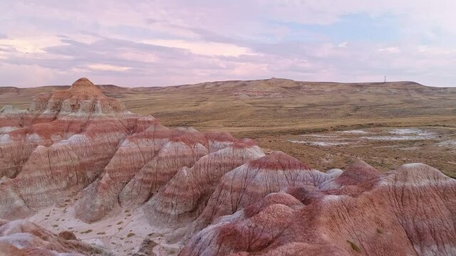 Flying over hilltops of red desert landscape at sunrise in Wyoming circling around the formations.