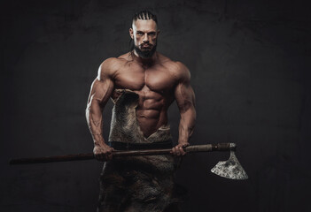 Prepared to battle viking with naked torso dreadlock and black beard posing holding his axe in dark...